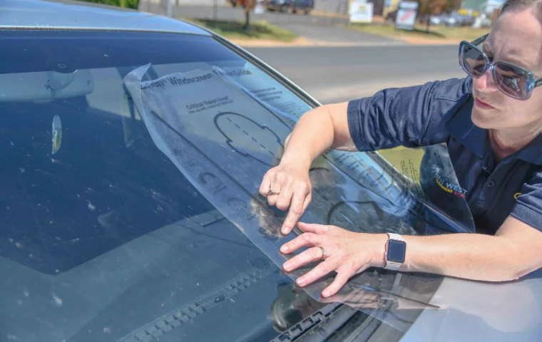 Mel owner of South West Windscreens & Tint inspecting chip damage on vehicle windscreen to assess repair or replacement.