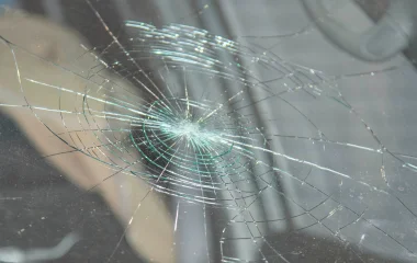 Close-up of a circular star-pattern crack on a car windscreen, demonstrating how laminated safety glass holds together under impact to protect passengers.